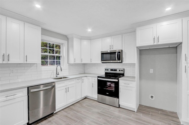 kitchen with white cabinets, decorative backsplash, stainless steel appliances, and sink