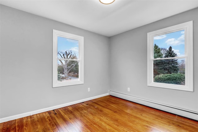 unfurnished room with light hardwood / wood-style floors, plenty of natural light, and baseboard heating