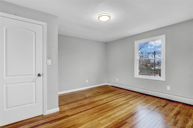 spare room with baseboard heating and light hardwood / wood-style flooring