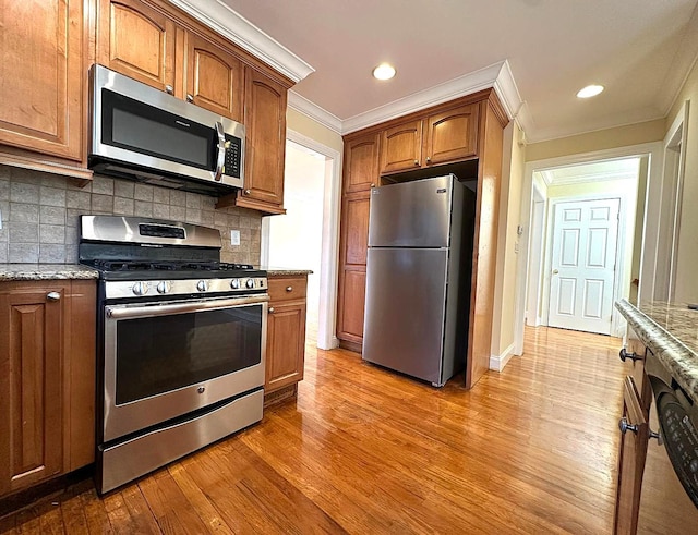 kitchen with appliances with stainless steel finishes, backsplash, ornamental molding, light hardwood / wood-style floors, and light stone countertops