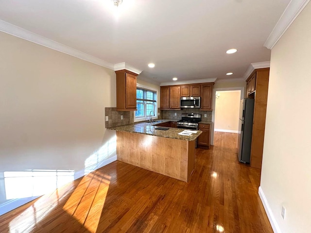 kitchen with tasteful backsplash, crown molding, kitchen peninsula, and appliances with stainless steel finishes