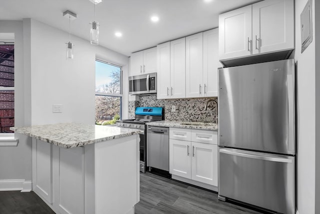 kitchen with light stone countertops, stainless steel appliances, sink, pendant lighting, and white cabinets