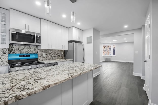 kitchen with backsplash, hanging light fixtures, light stone counters, white cabinetry, and stainless steel appliances