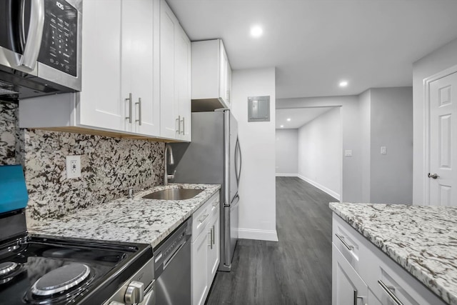 kitchen with light stone countertops, appliances with stainless steel finishes, dark wood-type flooring, sink, and white cabinets