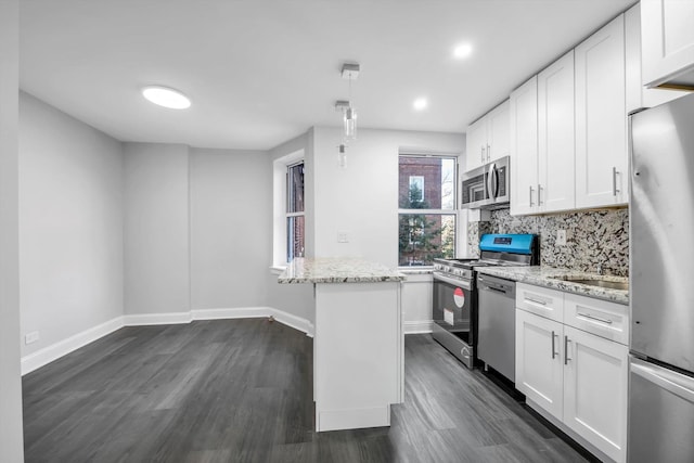 kitchen featuring white cabinets, a center island, stainless steel appliances, and light stone counters