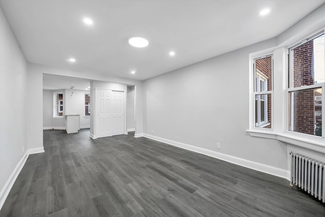 unfurnished living room featuring radiator heating unit and dark hardwood / wood-style floors