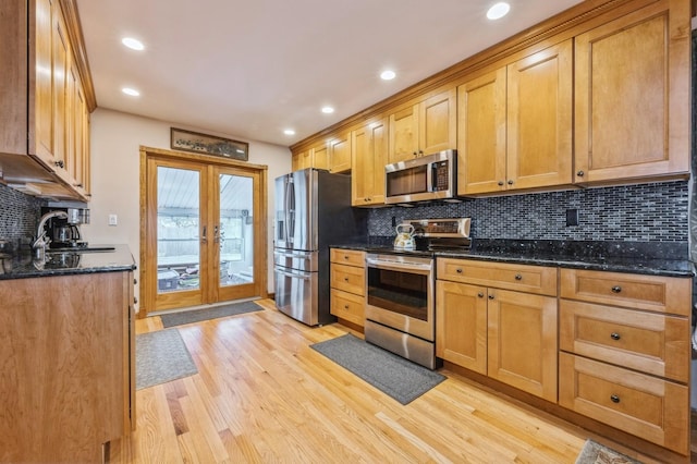 kitchen with dark stone counters, french doors, sink, light hardwood / wood-style flooring, and appliances with stainless steel finishes