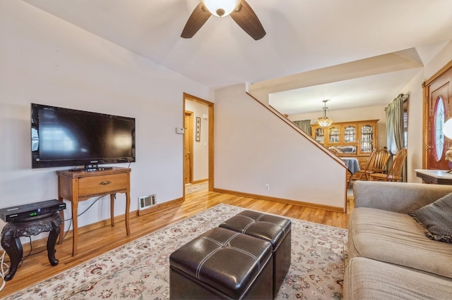 living room with ceiling fan with notable chandelier and wood-type flooring