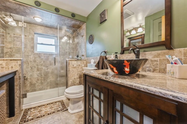 bathroom with tile patterned flooring, vanity, toilet, and a shower with door