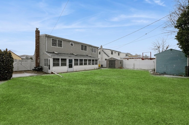 back of property with a sunroom, a shed, and a yard