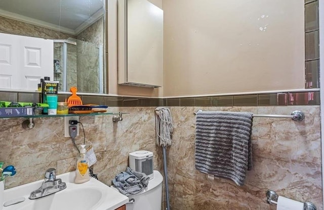 bathroom with vanity, toilet, ornamental molding, and tile walls