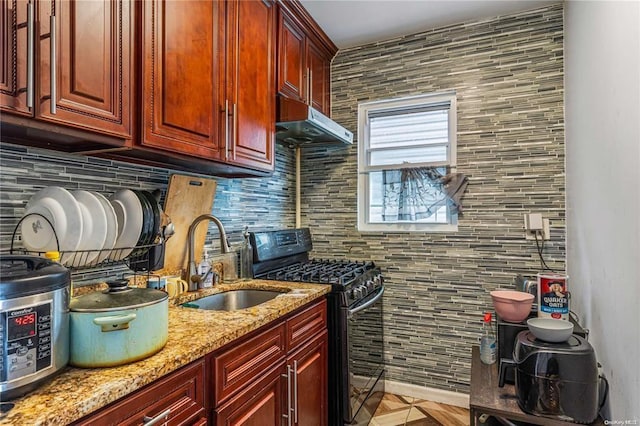 kitchen featuring decorative backsplash, light stone counters, black range with gas stovetop, sink, and light parquet flooring