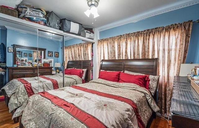 bedroom featuring multiple windows, ceiling fan, hardwood / wood-style floors, and ornamental molding