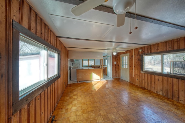 empty room featuring wood walls, light parquet flooring, and ceiling fan