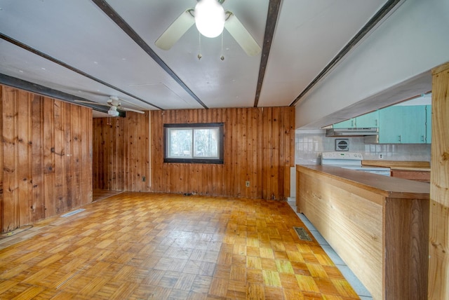 interior space with beam ceiling, wooden walls, light parquet floors, and ceiling fan