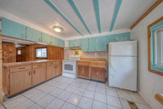 kitchen featuring kitchen peninsula, white appliances, ceiling fan, and wood walls