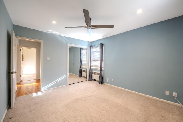 unfurnished bedroom featuring light carpet, radiator, and ceiling fan