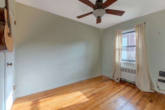 empty room with ceiling fan, radiator heating unit, and light hardwood / wood-style flooring