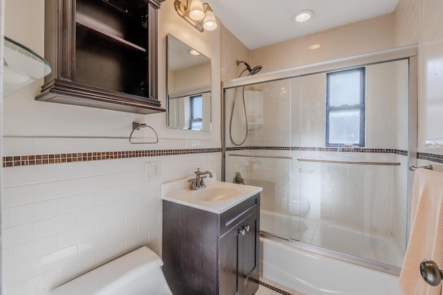 full bathroom with toilet, vanity, tile walls, and combined bath / shower with glass door