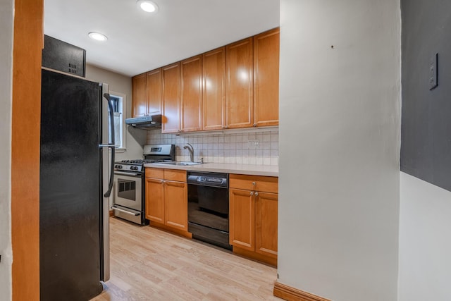 kitchen with light wood-type flooring, decorative backsplash, sink, and black appliances