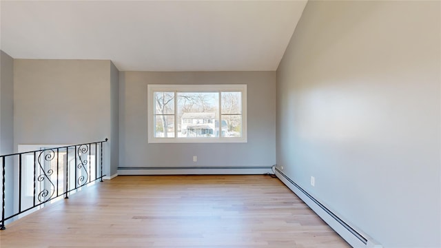 spare room featuring lofted ceiling, light hardwood / wood-style flooring, and baseboard heating