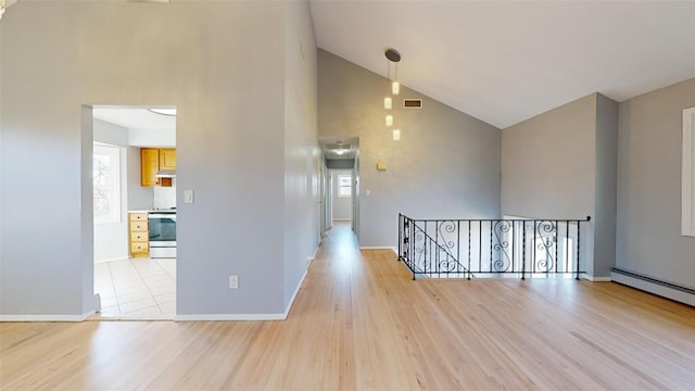 interior space featuring a baseboard heating unit, vaulted ceiling, and light wood-type flooring