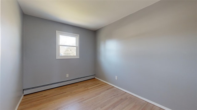 spare room with a baseboard heating unit and light hardwood / wood-style floors