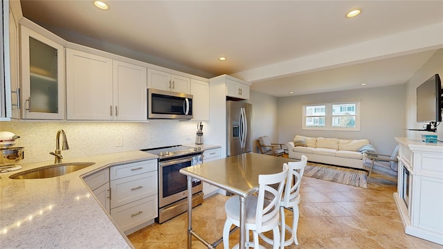 kitchen featuring light stone counters, sink, stainless steel appliances, and white cabinets