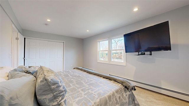 carpeted bedroom with baseboard heating and a closet