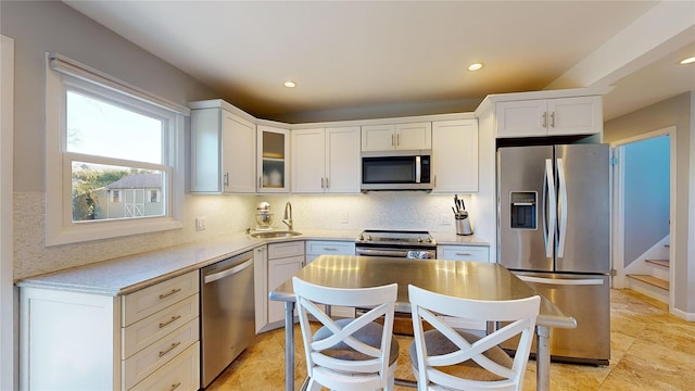 kitchen with stainless steel appliances, sink, decorative backsplash, and white cabinets