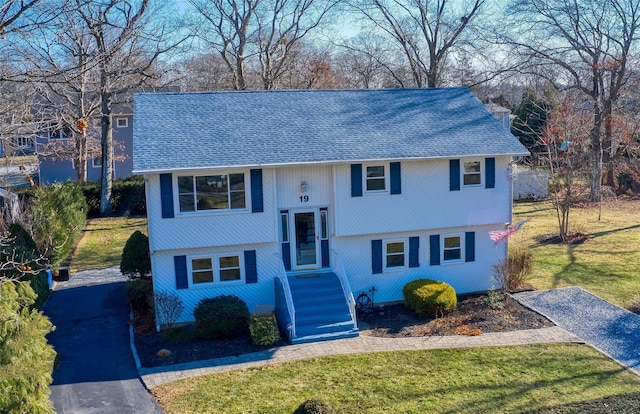 split foyer home with aphalt driveway, a front lawn, and a shingled roof