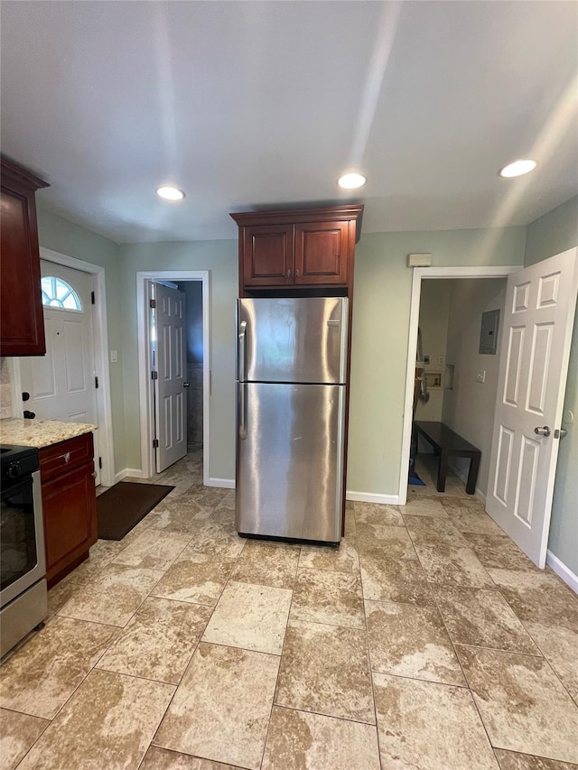 kitchen featuring electric panel, light stone counters, and appliances with stainless steel finishes