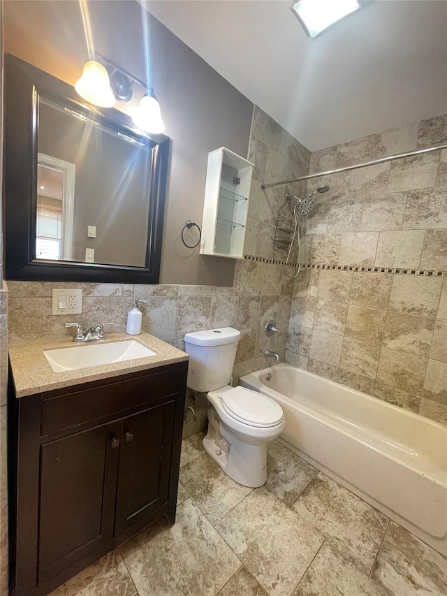 full bathroom with vanity, tiled shower / bath combo, toilet, tile walls, and tasteful backsplash