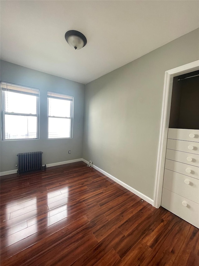 unfurnished bedroom featuring dark hardwood / wood-style floors and radiator heating unit