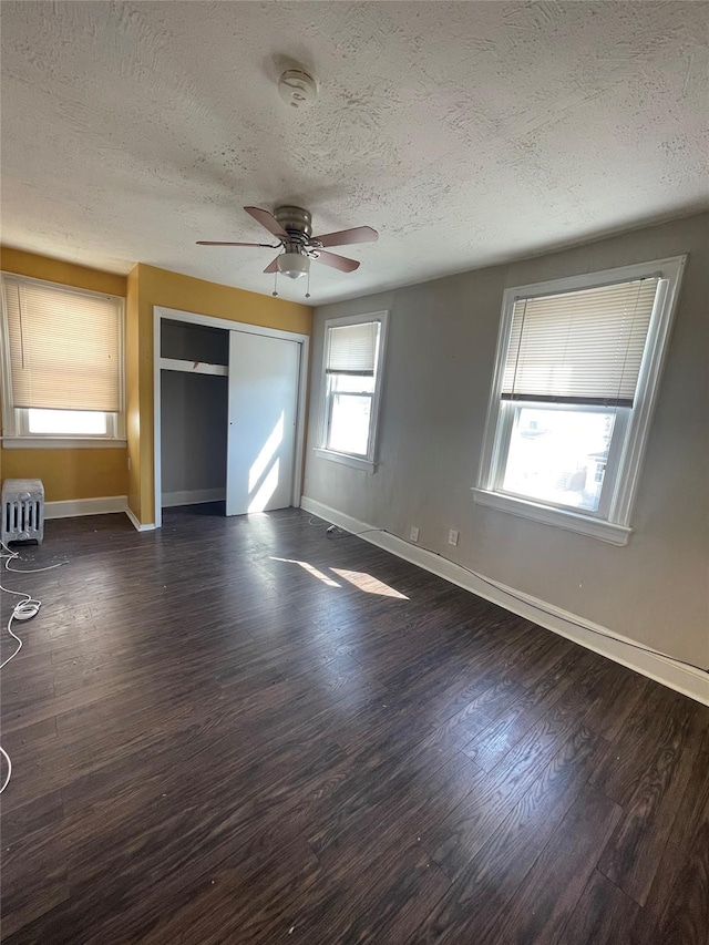 interior space with a textured ceiling, a closet, ceiling fan, and dark wood-type flooring