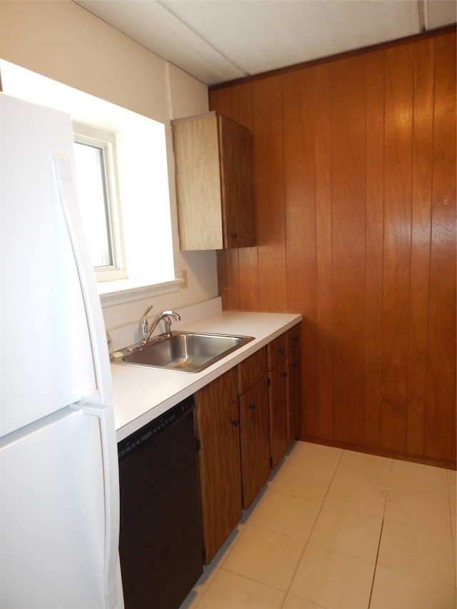 kitchen with wood walls, white refrigerator, sink, and black dishwasher