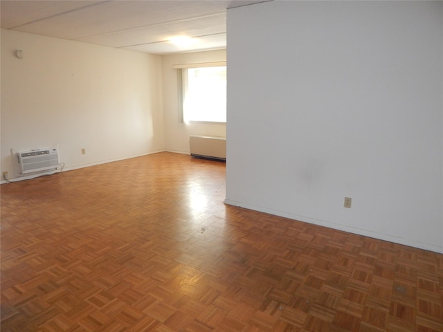 unfurnished room featuring a wall unit AC and dark parquet floors