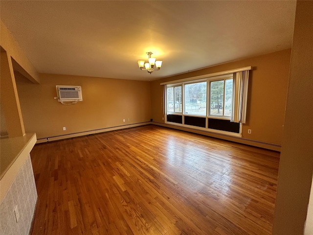 unfurnished room featuring hardwood / wood-style flooring, baseboard heating, a wall mounted AC, and an inviting chandelier