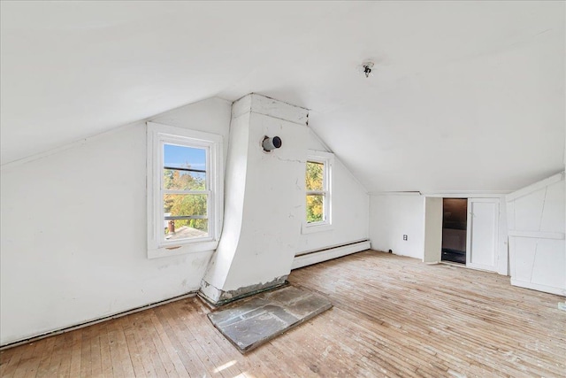 additional living space with light hardwood / wood-style flooring, a baseboard radiator, and lofted ceiling