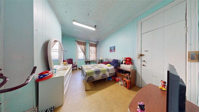 bedroom with a textured ceiling, light colored carpet, and wooden walls