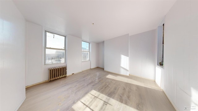 unfurnished room with radiator and light wood-type flooring