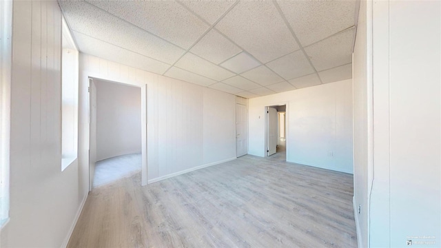 unfurnished room with a drop ceiling and light hardwood / wood-style flooring