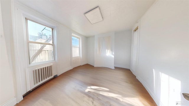 empty room with radiator heating unit and light wood-type flooring