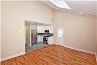 unfurnished living room featuring vaulted ceiling with skylight and wood-type flooring