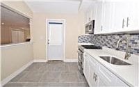 kitchen with dark tile patterned flooring, backsplash, white cabinetry, and sink