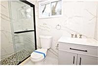 bathroom featuring vanity, toilet, an enclosed shower, and tile walls