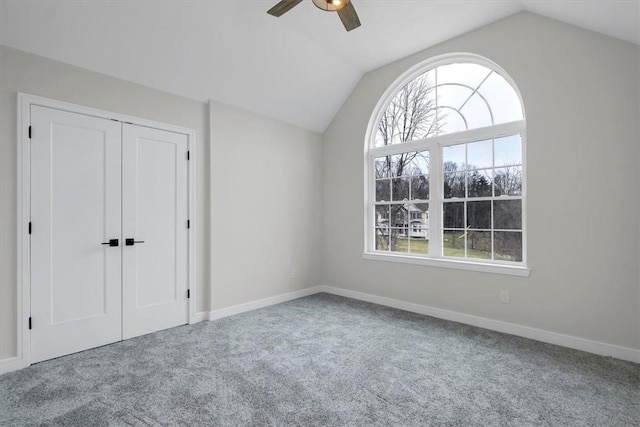 unfurnished bedroom with carpet flooring, ceiling fan, a closet, and lofted ceiling