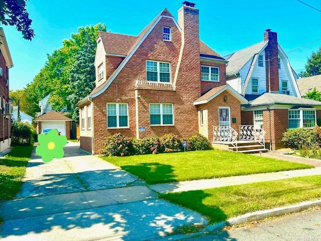 tudor house with a front yard, an outbuilding, and a garage