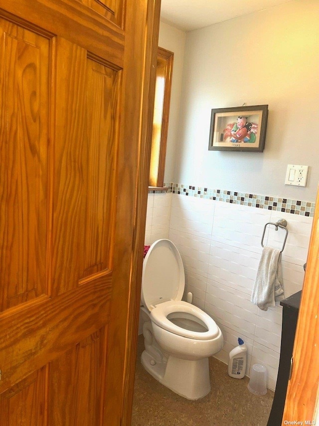 bathroom featuring tile patterned floors, tile walls, and toilet