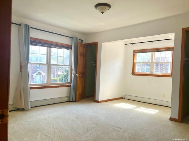 unfurnished bedroom featuring light colored carpet and baseboard heating